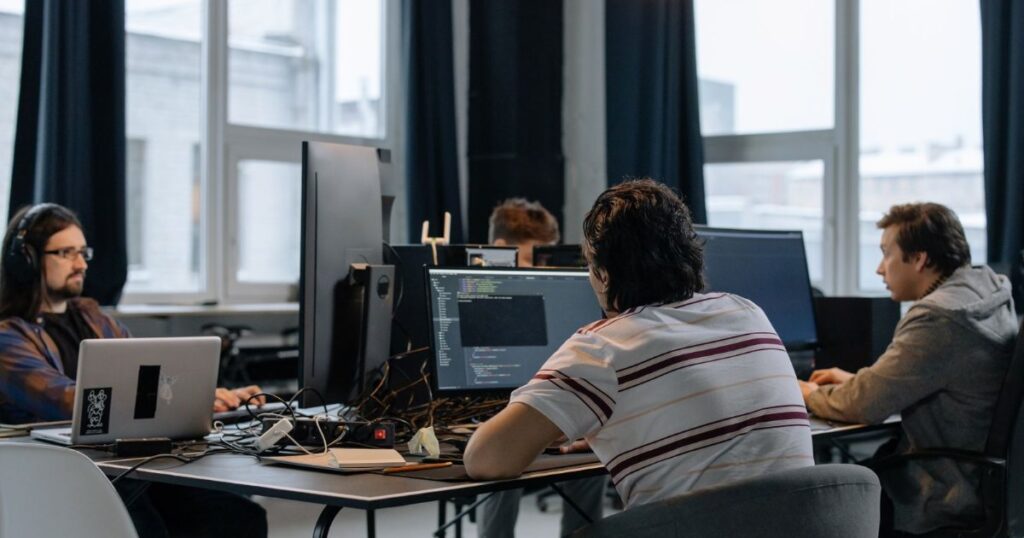Team of software developers working on computers in a tech office.