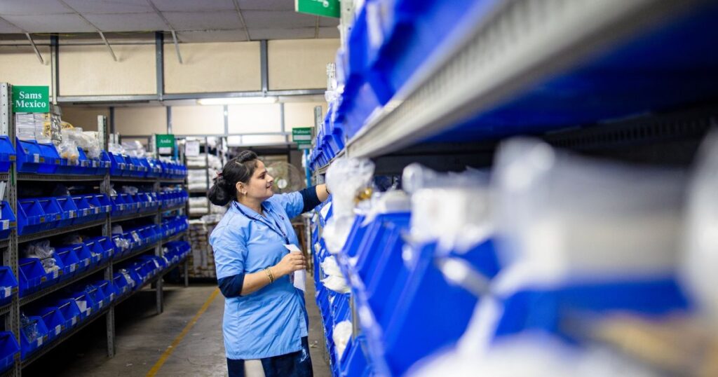 A warehouse worker organizing inventory on shelves with labeled bins.