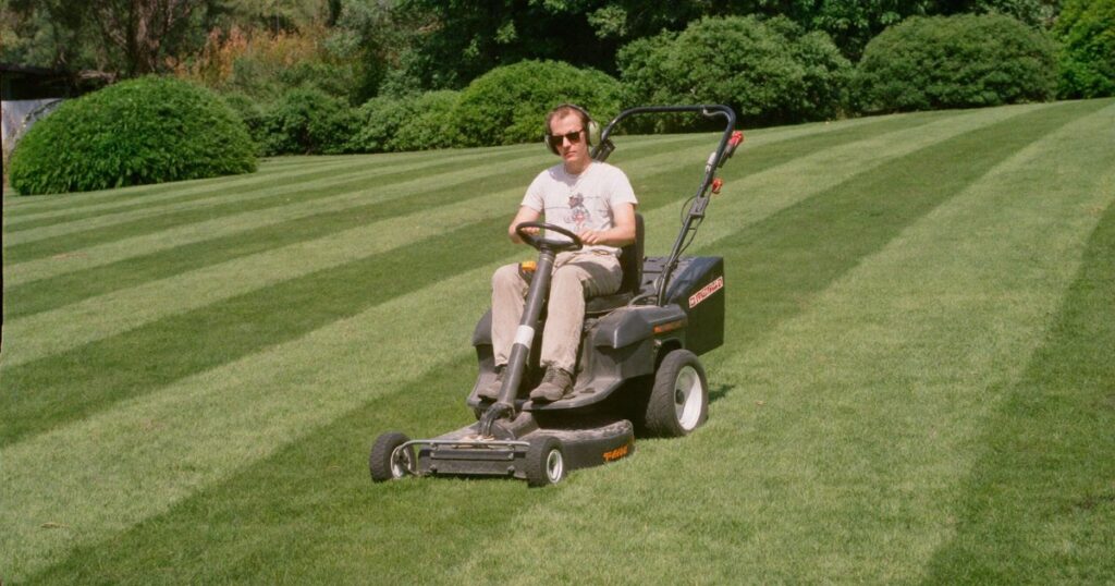 Landscaper mowing a large residential lawn